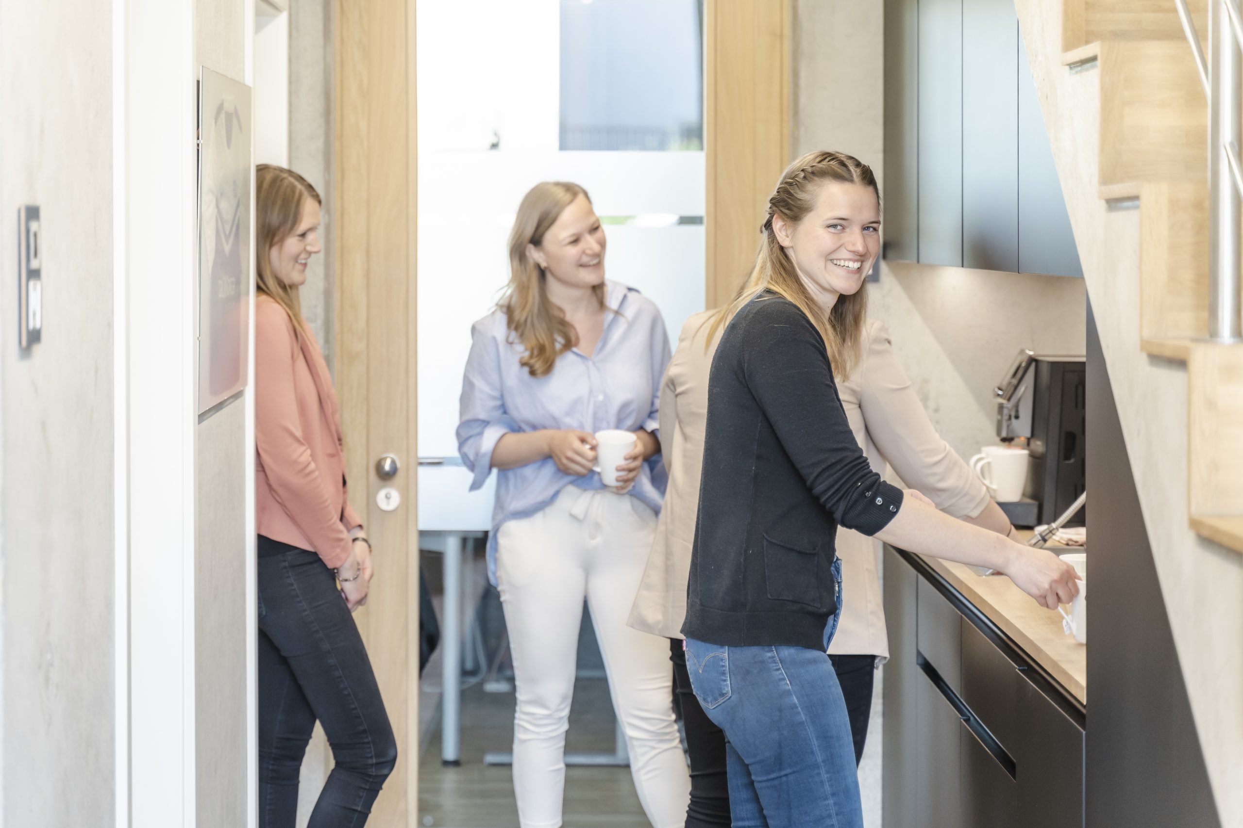 Mitarbeiterinnen der Gronover Gruppe stehen gemeinsam in der Küche der Gronover Elektrotechnik und reden miteinander während sie sich Kaffee zubereiten